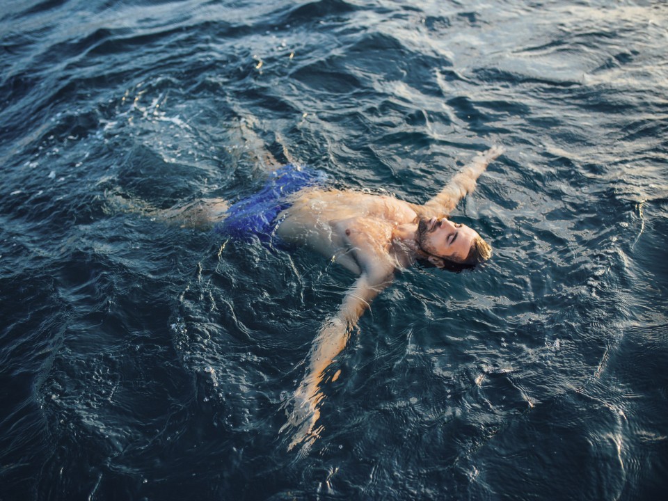 Mann schwimmt im Meer und hat dabei die Augen geschlossen____