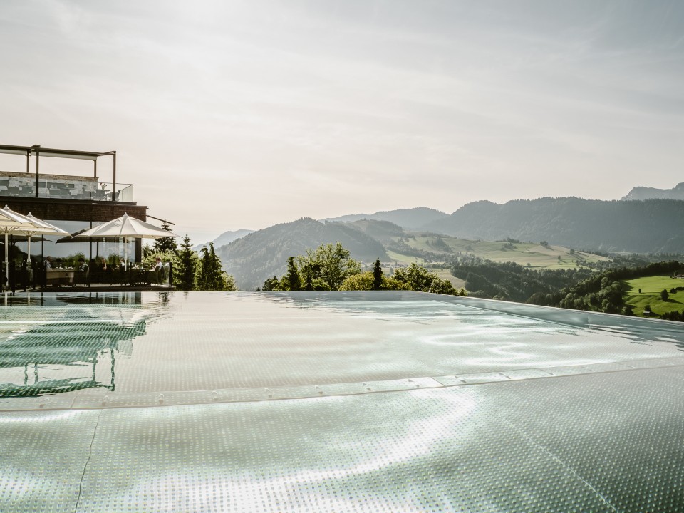 Sicht auf den Infinity Pool des Bergkristall Hotels und das Gebirge im Hintergrund____