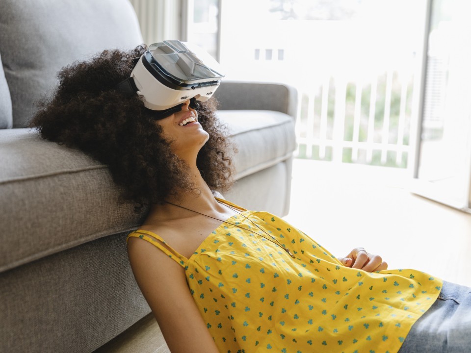 Frau mit VR-Brille hat den Kopf auf die Couch gelehnt____
