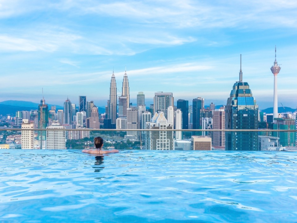 Frau im Infinity Pool mit Blick auf die Skyline Singapurs.____